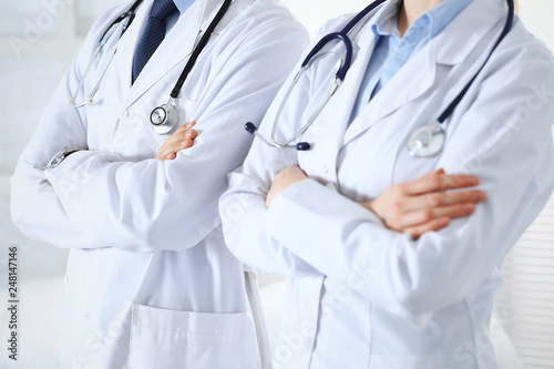 Team of unknown doctors standing straight with arms crossed in hospital. Physicians ready to help. Healthcare, insurance and medicine concept