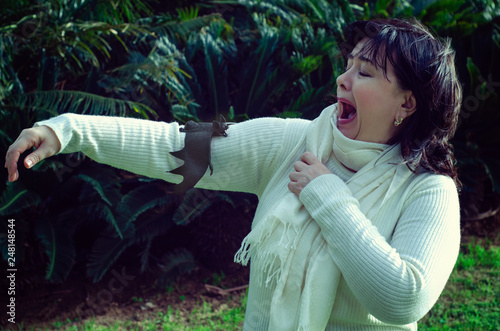 Woman screams in fear because a bat has landed on her arm photo