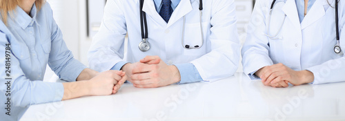 Doctor and patient sitting at the desk, close-up of unknown physician at work. Medicine and health care concept