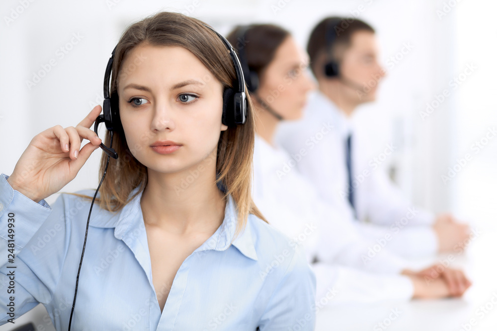 Call center operators. Focus on young cheerful smiling woman in headset. Business and customer service concepts Call center operators. Focus on young cheerful smiling woman in headset. Business and customer service concepts