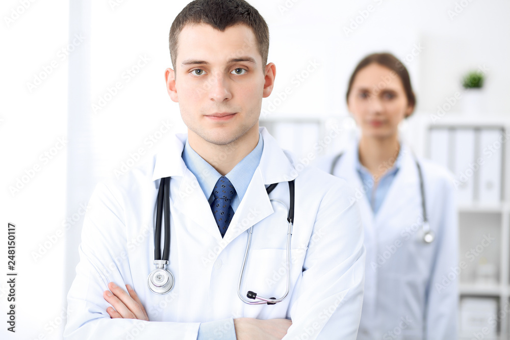 Friendly male doctor on the background of a female physician in hospital office Friendly male doctor on the background of a female physician in hospital office
