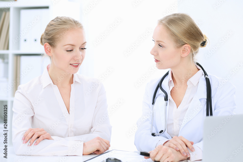 Doctor and patient talking in hospital office while sitting at the desk. Health care and client service in medicine Doctor and patient talking in hospital office while sitting at the desk. Health care and client service in medicine