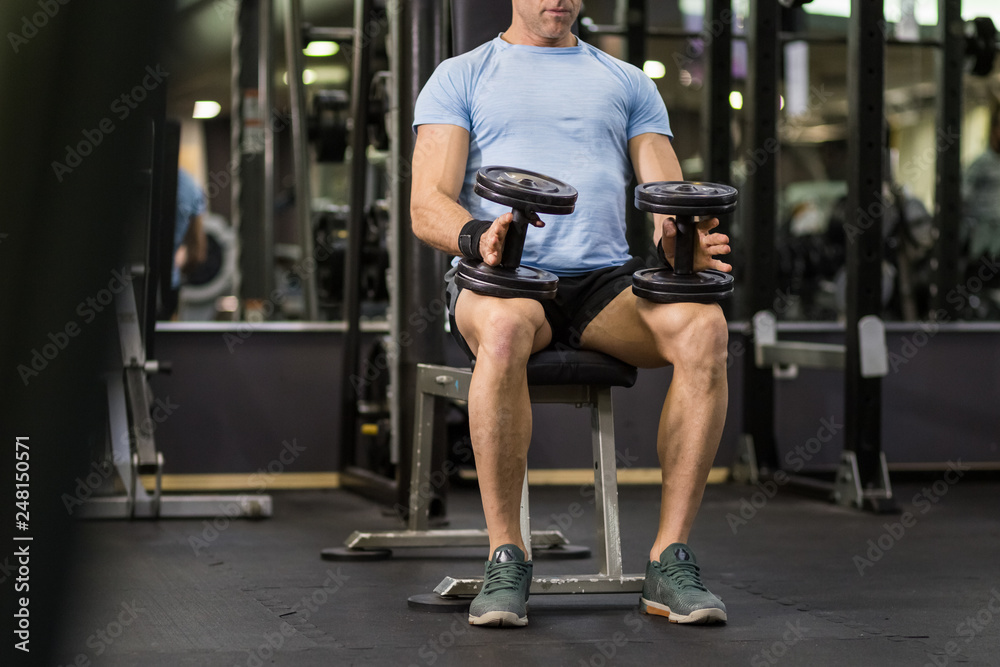 Fototapeta premium Muscular man holding dumbbell at the gym.