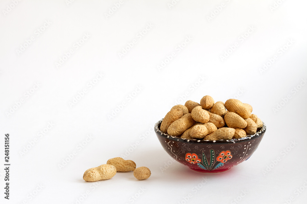 nuts in shell on clay cup on white background, copy space for text