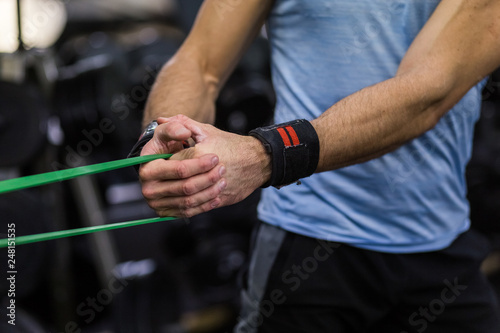 Man doing side-to-side chops exercise with elastic band at the gym.