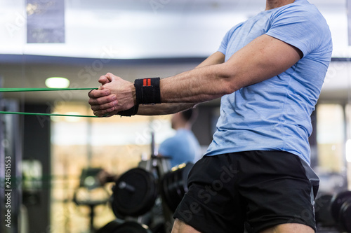 Man doing side-to-side chops exercise with elastic band at the gym.