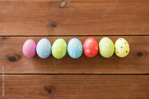 easter, holidays and tradition concept - row of colored eggs on wooden table
