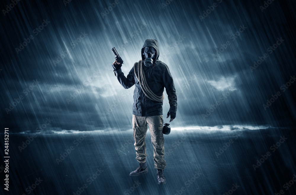 Terrorist in a stormy space with gas mask on his hand and weapons on his arm
