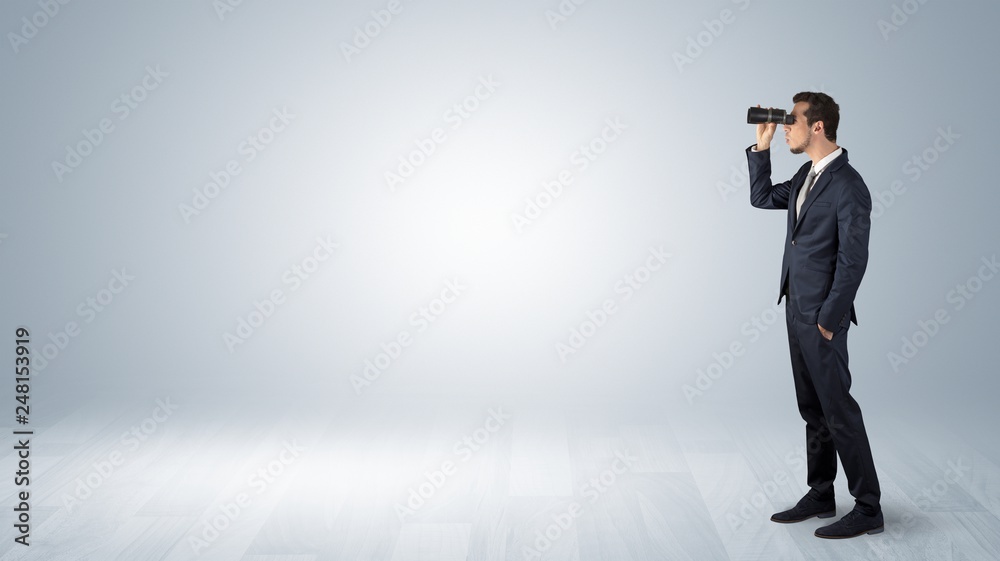 Fototapeta premium Businessman looking forward with binoculars in an empty space 