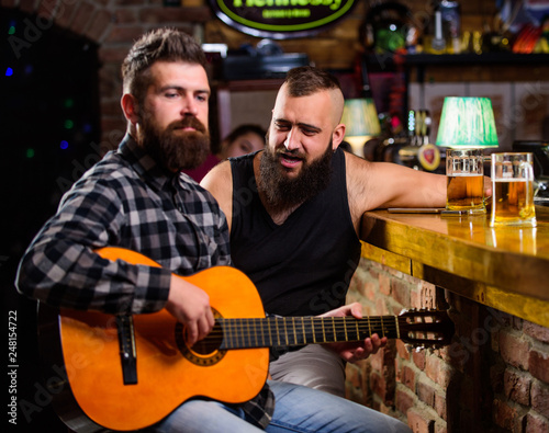 Friday relaxation in bar. Friends relaxing in bar or pub. Real men leisure. Hipster brutal bearded spend leisure with friend in bar. Man play guitar in bar. Cheerful friends relax with guitar music © be free