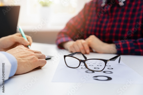 eye health - black glasses on eyesight test chart in optician office