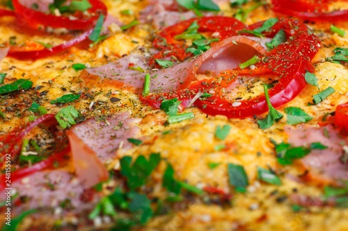 Close up Italian pizza with ham, cheese, pepper and herbs on a brown table decorated by mushrooms, red sweet pepper and cherry tomatoes