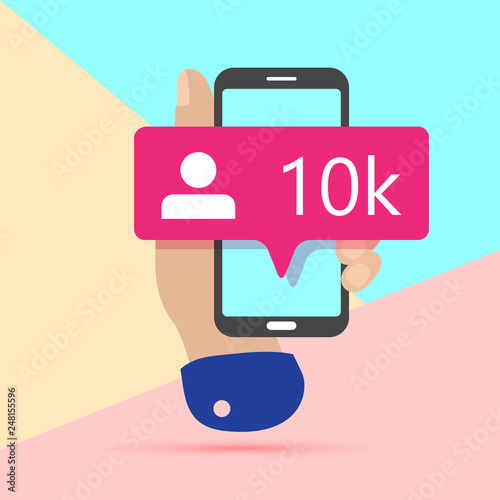 modern minimal hand holding mobile phone with new pink ten chiliad like followers social media iconon screen with shadow on pastel colored blue and background. Pink bubble  icon set for websites, blog photo