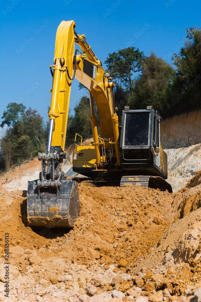 Obraz premium Industrial excavator working on construction site to clear the land of sand and soil