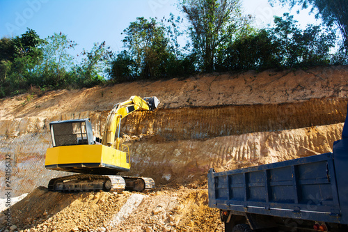 Industrial excavator and truck working on construction site to clear the land of sand and soil photo