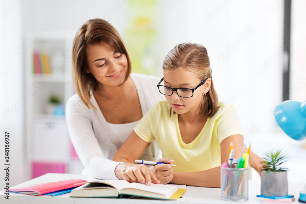 education, family and learning concept - mother and daughter doing homework together at home education, family and learning concept - mother and daughter doing homework together at home