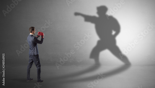Businessman fighting with his strong karate man shadow
