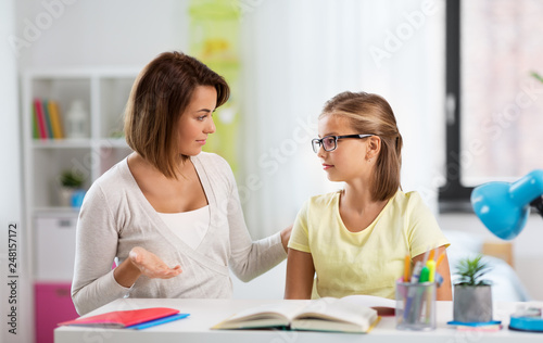education, family and learning concept - displeased mother talking to daughter while doing homework at home