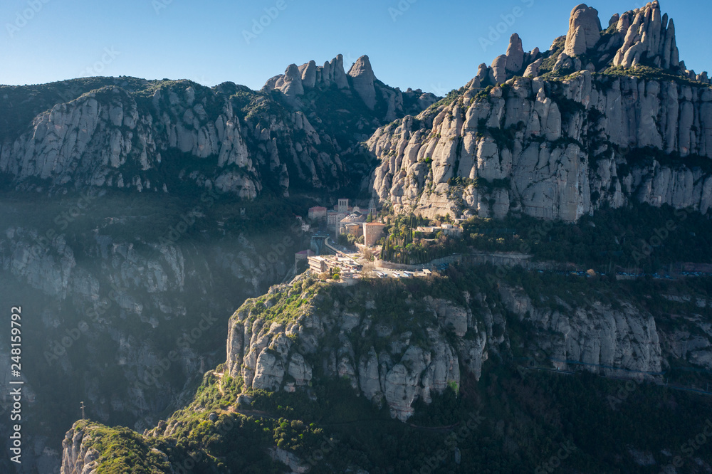 Aerial; drone view of multi-peaked mountain range near Barcelona; site of the Benedictine abbey, Santa Maria de Montserrat; can be reached by road, by the Aeri cable car or Rack Railway; Spain