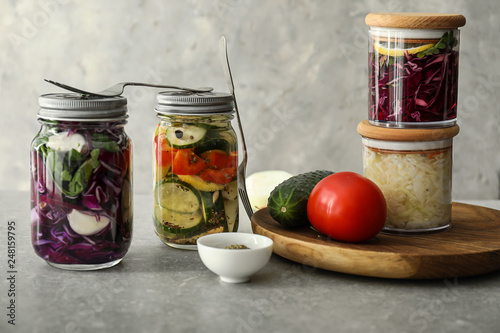 Glass jars with fermented vegetables on grey table