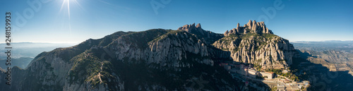 Aerial; wide panorama of famous abbey homonymous mountain range Montserrat; tourist attractions route of Spain; drone view of steep stone slope with many limestone rocks; religious symbol of Catalonia