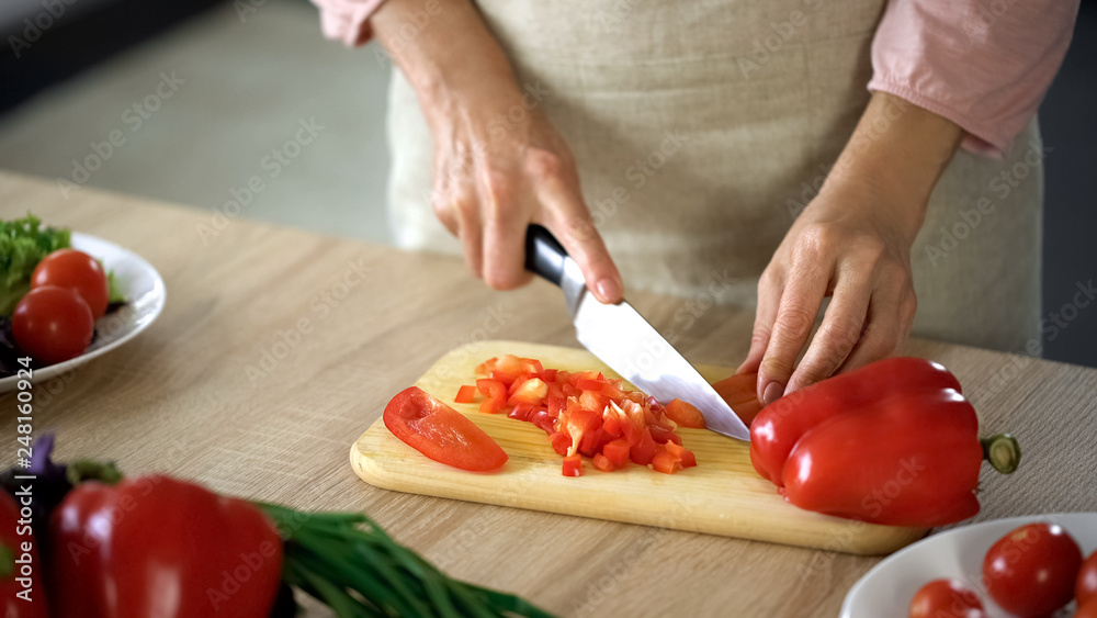Female chef cutting fresh pepper on board kitchen, cooking salad, culinary show