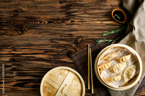 Bamboo steamer with tasty Japanese gyoza on wooden table