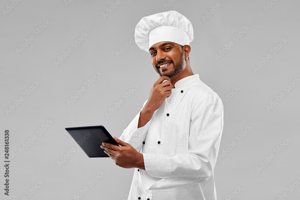 cooking, technology and people concept - happy male indian chef in toque with tablet computer over grey background cooking, technology and people concept - happy male indian chef in toque with tablet computer over grey background