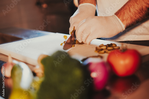 Kitchen chef cuttign cucumber with a knife