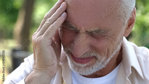 Senior man suffering headache, migraine attack during walk, risk of thrombus