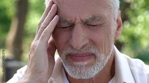 Mature man feeling sudden sharp pain in head, migraine attack, risk of thrombus photo