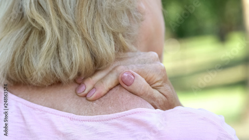 Foto Mature woman massaging numb neck and shoulders, spine injury consequences