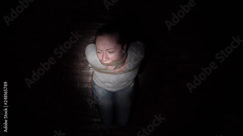 bound prisoner to chair sits in dark room under beam of light. top view.