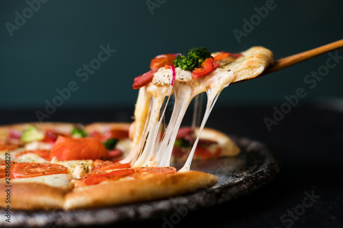 Tasty sliced pizza with basil leaves on black table