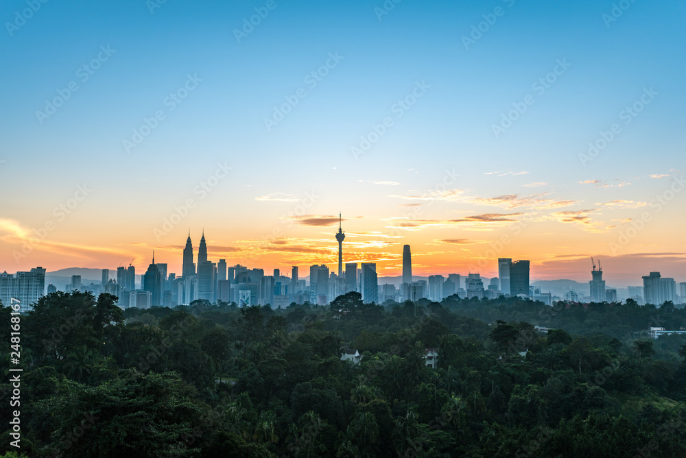 Cityscape of Kuala Lumpur, Malaysia surrounded by trees during sunrise