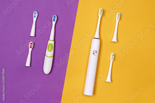 Adult and baby smart electric toothbrushes. Modern technology for health. Healthy teeth. Dentistry. Medical robot. Purple and yellow paper background