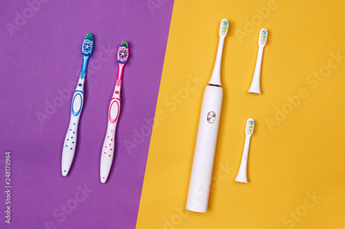 Manual and electric toothbrushes on pink coral background. Dental care