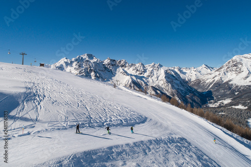 Skiers and snowboarders on the track, ski station in the Italian Alps. Valtellina.