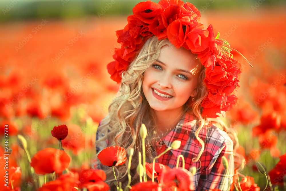 Naklejka premium Portrait of a girl on the street with a wreath of poppy flowers on the head