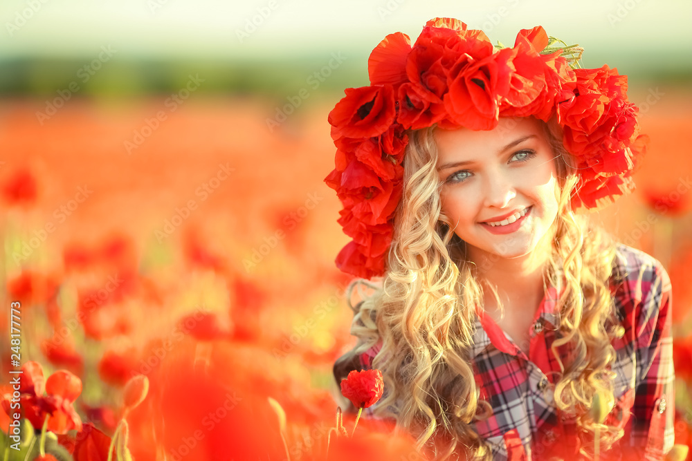 Naklejka premium Portrait of a girl on the street with a wreath of poppy flowers on the head