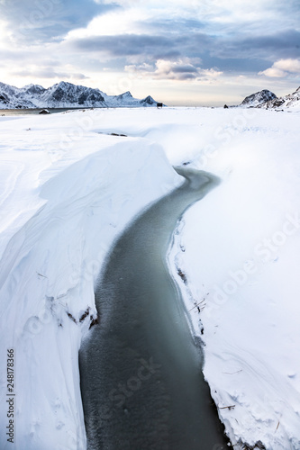 frozen creek on Haukland Beach and snow-covered mountains, Lofoten Islands, Norway © Giuma