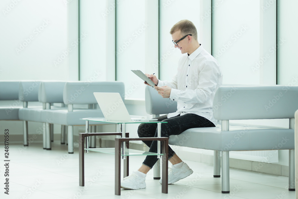 employee of the company reads a business document sitting in the office lobby employee of the company reads a business document sitting in the office lobby