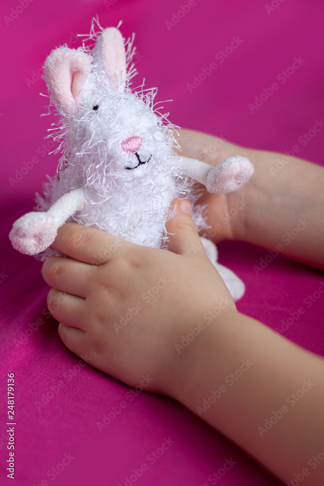 Handles of the child hold a toy hare.