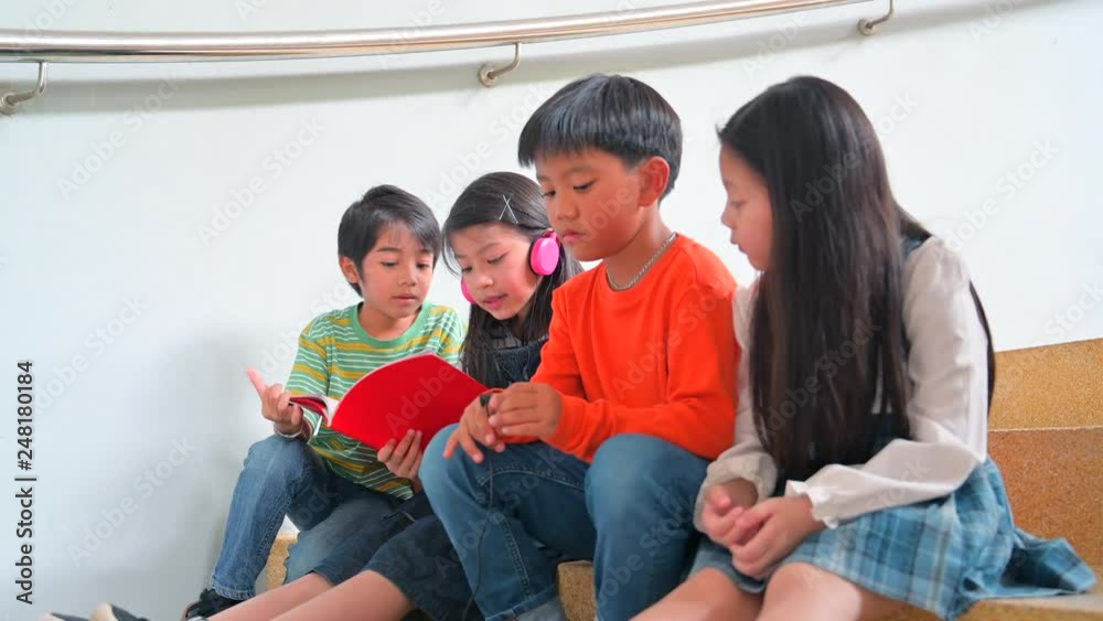 Large group of young boys and girls sharing a tablet and smart phone technology