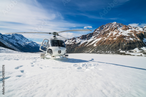 Helicopter landing on snow mountain in tasman glacier in Mt Cook, New Zealand. The helicopter service in Mt Cook offers scenic flights, glacier landing and emergency rescue. photo