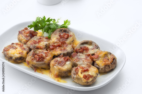 Cheese and bacon stuffed mushroom caps baked in the oven on white background