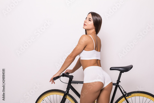 Fototapeta Naklejka Na Ścianę i Meble -  Portrait of a smiling woman standing near bicycle on white background.
