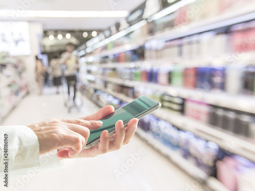 Digital lifestyle business person or shopper using mobile smart phone for retail shopping in supermarket