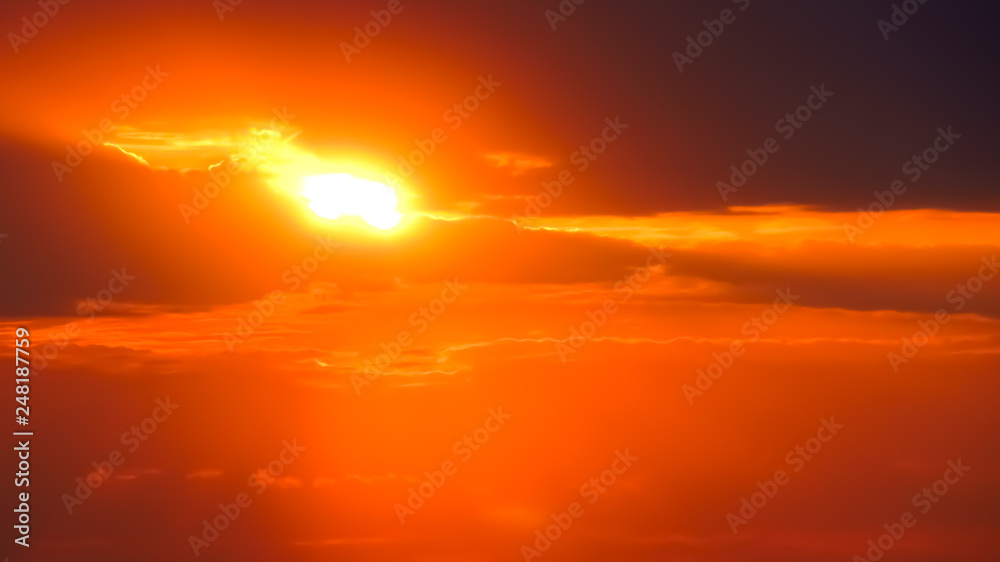 Defocused image of an orange sunrise in the clouds.