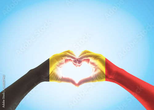 Belgian black yellow red flag pattern on people heart shaped hands  clipping path  on sky background